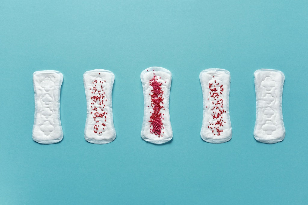 period pads in a row, some with more red beads on it than others