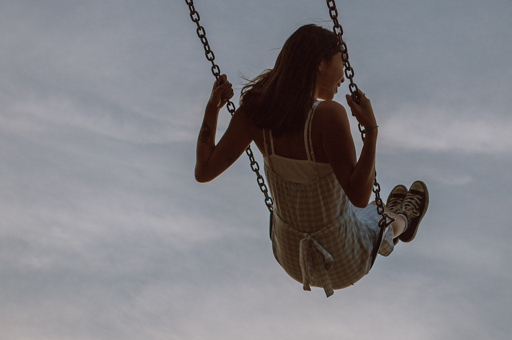 girl swinging from rope swing with a dark blue sky background